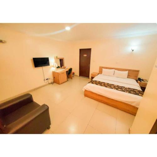 a bedroom with a bed and a couch and a television at Best Connection Airport Hotel in Lagos