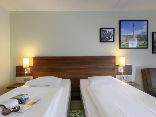 two beds in a hotel room with glasses on them at Mercure Stuttgart Sindelfingen an der Messe in Sindelfingen
