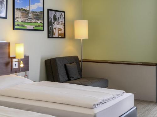a hotel room with a bed and a chair at Mercure Stuttgart Sindelfingen an der Messe in Sindelfingen