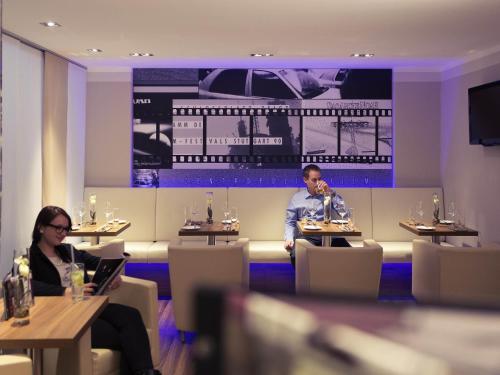 a man and a woman sitting at tables in a restaurant at Mercure Stuttgart Sindelfingen an der Messe in Sindelfingen