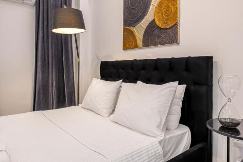 a bedroom with a bed with a black headboard and white pillows at Aqua Bliss Piraeus in Piraeus