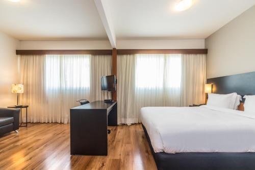 a hotel room with a bed and a television at Paraíso Suítes by Charlie in Sao Paulo