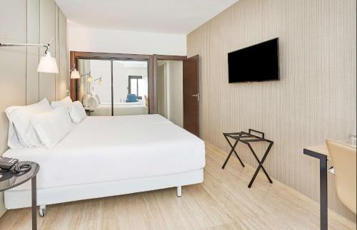 a hotel room with a white bed and a television at NH Imperial Playa in Las Palmas de Gran Canaria