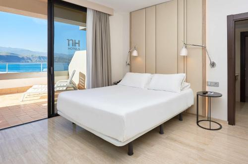 a bedroom with a large white bed and a balcony at NH Imperial Playa in Las Palmas de Gran Canaria