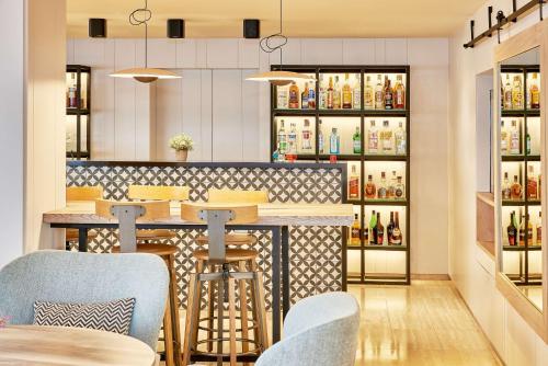 a bar with blue chairs and bottles of alcohol at NH Imperial Playa in Las Palmas de Gran Canaria