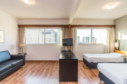 a hotel room with a bed and a couch at Paraíso Suítes by Charlie in Sao Paulo