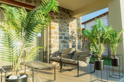 a patio with plants and a couch and tables at Piedra Luxury Apartments in Nafplio