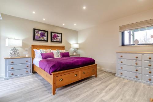 a bedroom with a purple bed and a window at White House Lodges - Nightingale in Heveningham