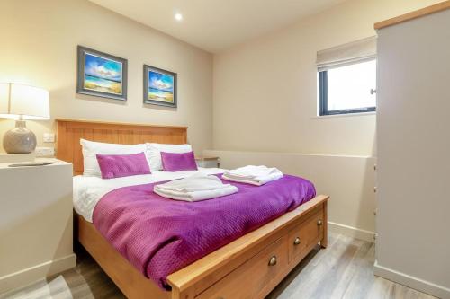 a bedroom with a large bed with purple sheets at White House Lodges - Nightingale in Heveningham