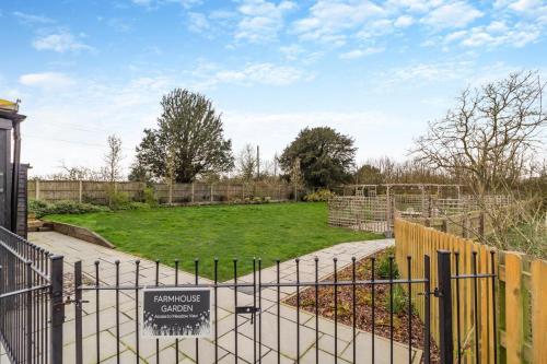 a gate with a sign in front of a garden at White House Lodges - Nightingale in Heveningham