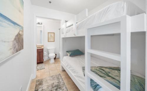 een wit stapelbed in een witte kamer met een toilet bij Laketown Wharf 1134 in Panama City Beach