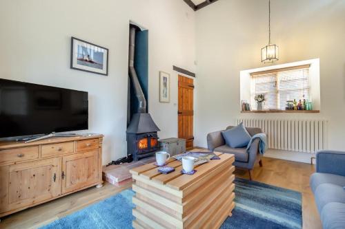 a living room with a tv and a fireplace at Grove Barn in Langham