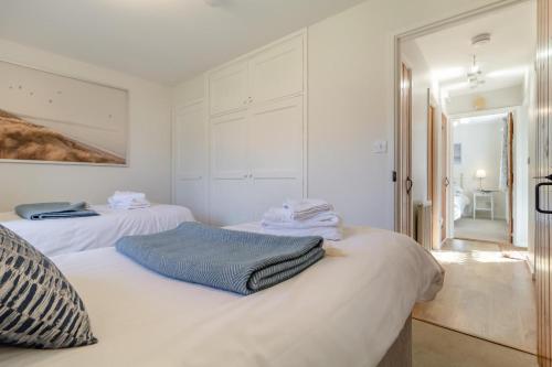 two beds in a room with white walls at Grove Barn in Langham