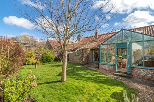 a brick house with a tree in the yard at Grove Barn in Langham