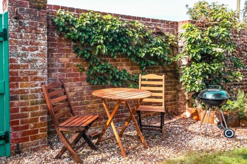 a table and chairs next to a brick wall at Grove Barn in Langham