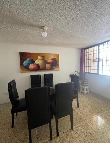 a dining room with a table and chairs and a painting at Habitacion con aire y baño privado in Valledupar