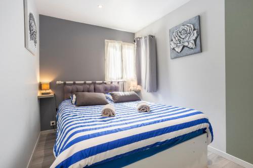 a bedroom with a bed with a blue and white striped blanket at L'Eclose in Le Guilvinec