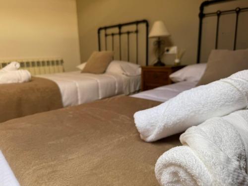 a hotel room with three beds with towels at Albergue Internacional in Sarria