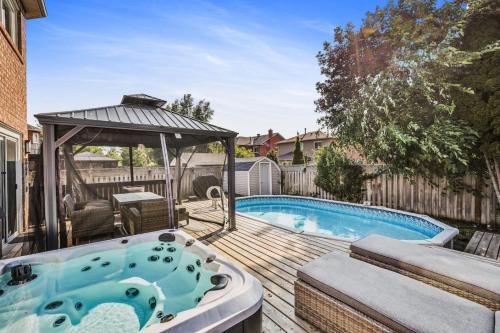 a hot tub on a deck next to a swimming pool at Luxe 4BR Retreat w Heated Pool Hot Tub and BBQ in Whitby