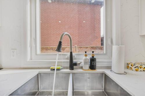 a kitchen sink with two bottles on a window at Luxe 4BR Retreat w Heated Pool Hot Tub and BBQ in Whitby