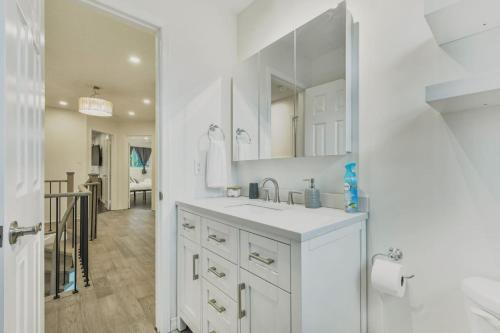 a white bathroom with a sink and a mirror at Luxe 4BR Retreat w Heated Pool Hot Tub and BBQ in Whitby