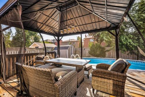 a patio with a table and chairs and a pool at Luxe 4BR Retreat w Heated Pool Hot Tub and BBQ in Whitby