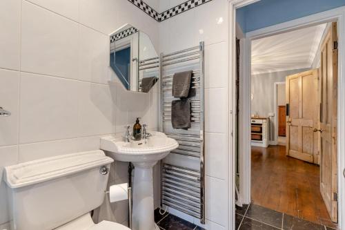 a white bathroom with a sink and a toilet at Swallows Way in Briston
