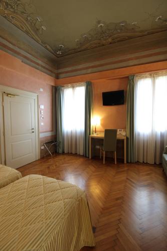 VazzolaにあるHotel Villa Materniniのベッドと机と窓のある寝室