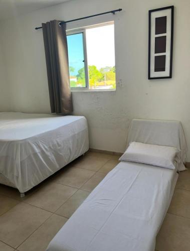 a bedroom with two beds and a window at Flat - Jacumã - Conde in Conde