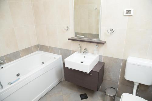 a bathroom with a sink and a tub and a toilet at Zoi Apartments in Dobrovo