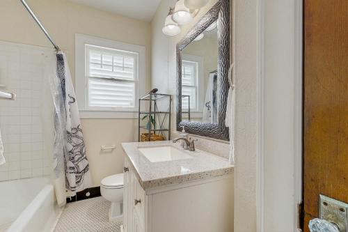 a bathroom with a sink and a toilet and a mirror at Sea Glass Cottage in Galveston