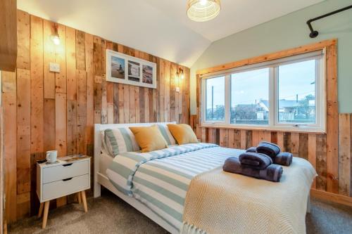een slaapkamer met houten wanden, een bed en een raam bij The Shack in Lessingham