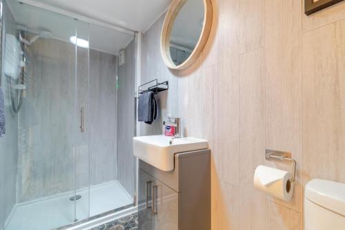 een badkamer met een wastafel, een douche en een spiegel bij The Shack in Lessingham