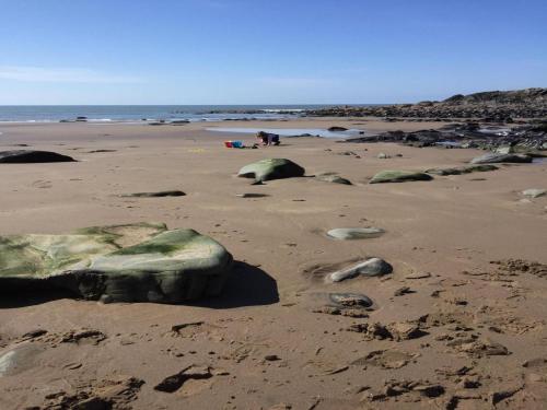 a beach with rocks in the sand and the ocean at Greenburn in Leswalt