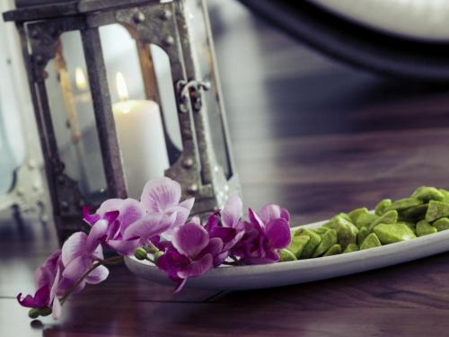 a plate with purple flowers and a candle on a table at Mercure Hotel Hamm in Hamm