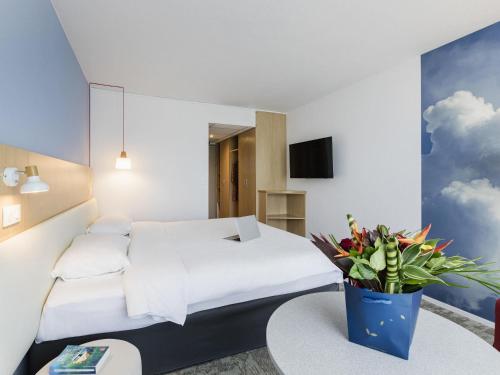 a hotel room with a bed and a vase of flowers at ibis Styles Aix les Bains Domaine de Marlioz in Aix-les-Bains