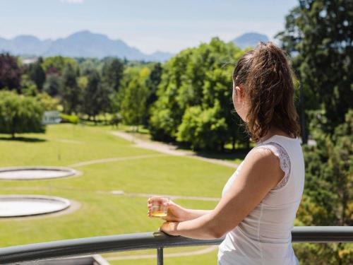 a woman standing on a balcony looking at a park at ibis Styles Aix les Bains Domaine de Marlioz in Aix-les-Bains