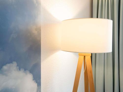 a lamp with a white shade next to a wall at ibis Styles Aix les Bains Domaine de Marlioz in Aix-les-Bains