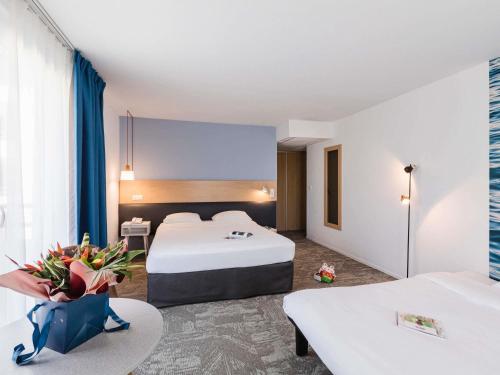 a hotel room with two beds and a table at ibis Styles Aix les Bains Domaine de Marlioz in Aix-les-Bains
