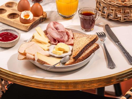 a plate of food on a table with eggs meat and bread at ibis Styles Aix les Bains Domaine de Marlioz in Aix-les-Bains
