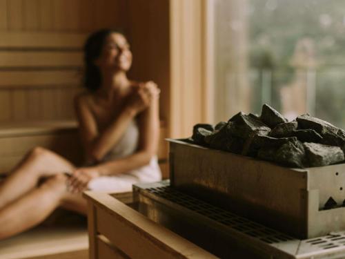 a woman sitting on a bed next to a box of coal at ibis Styles Aix les Bains Domaine de Marlioz in Aix-les-Bains