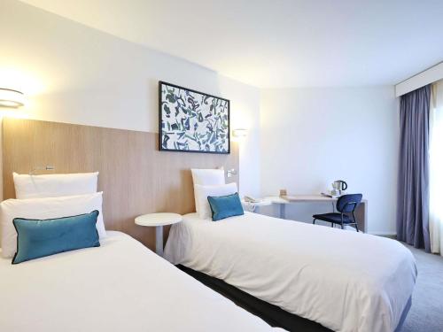 a hotel room with two beds and a desk at Mercure Grenoble Centre Porte des Alpes in Grenoble