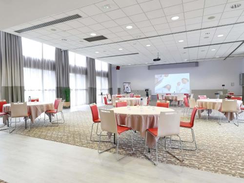a conference room with tables and chairs and a projection screen at Mercure Grenoble Centre Porte des Alpes in Grenoble