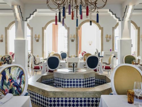 a restaurant with a fountain in the middle of a room at Le Médina Essaouira Thalassa Sea & Spa - MGallery Collection in Essaouira