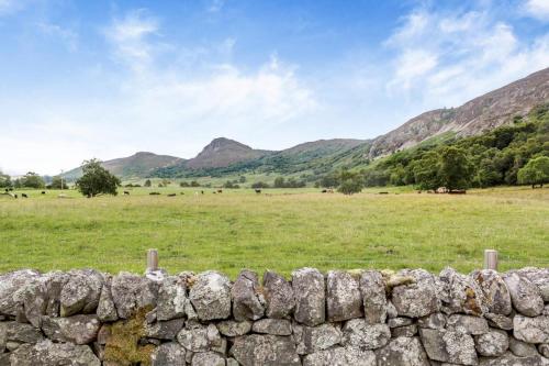 a stone wall in a field with mountains in the background at 1 Bed in Newtonmore oc-a32412 in Newtonmore