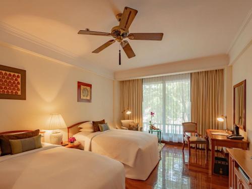 a hotel room with two beds and a ceiling fan at Sofitel Angkor Phokeethra Golf & Spa Resort in Siem Reap