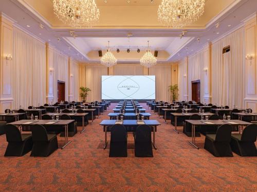 a large banquet hall with tables and a projection screen at Sofitel Angkor Phokeethra Golf & Spa Resort in Siem Reap