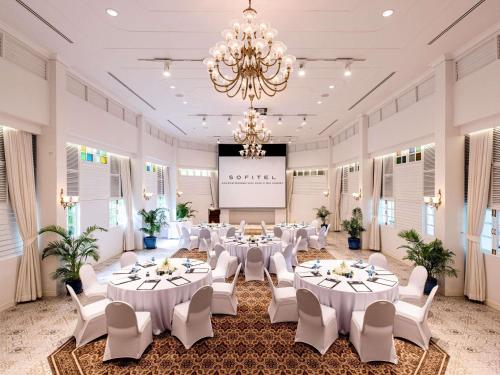 a banquet hall with white tables and chairs and a projection screen at Sofitel Angkor Phokeethra Golf & Spa Resort in Siem Reap