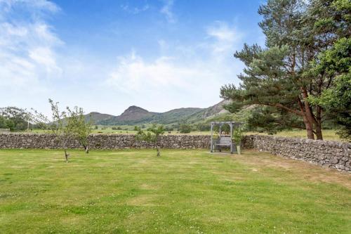 a park with a stone wall and a swing at 3 Bed in Newtonmore oc-h32416 in Newtonmore