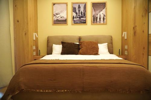 a bedroom with a large bed with four pictures on the wall at La Dimora delle Nevi in Aosta
